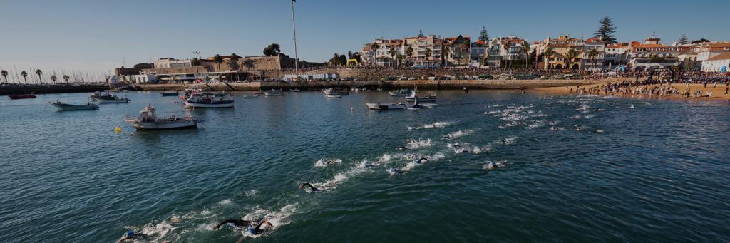 Athletes going into the Water at the IRONMAN 70.3 Portugal Cascais with the City in the Background
