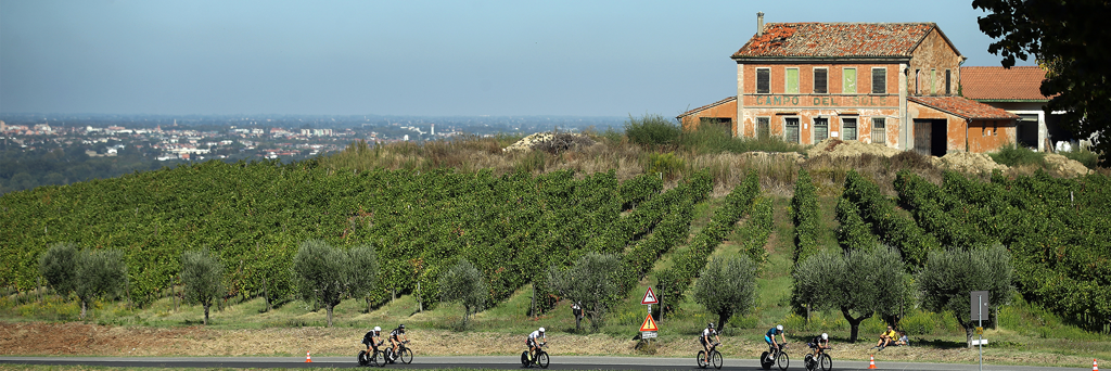 5150 Cervia athletes on their bikes through the countryside of Romagna next to fields and on a hill with views of the city center