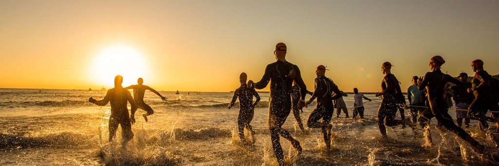 IRONMAN 70.3 Durban athletes are running into the Indian Ocean at uShaka Beach near the Durban Harbour at sunrise