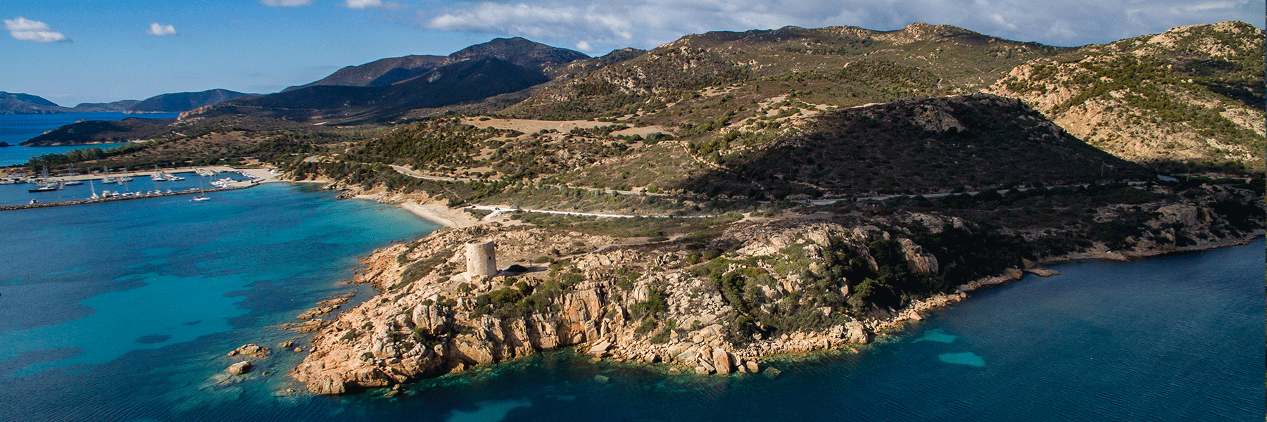 Wide angle image of the Sardinian rugged coast covered with green bushes and trees next to the clear water of the Mediterranean Sea in Santa Margeritha di Pula