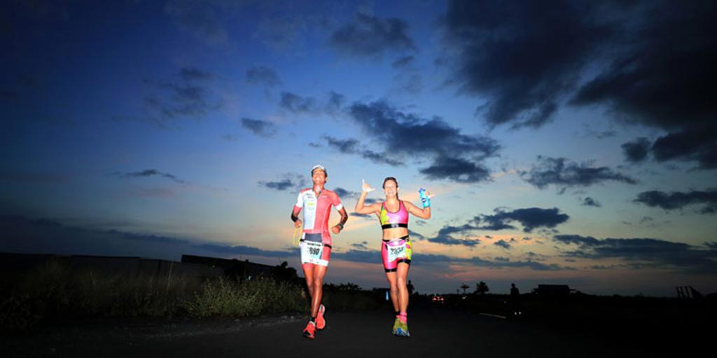 Triathletes running in front of a dark sky