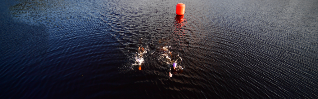 Athletes swimming in Syväri lake in the protected Tahko Bay in Finland