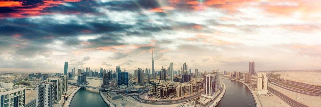 Panoramic view of Dubai Downtown skyline including highest building in the world - Burj Khalifa - and sand dunes at sunset with red clouds