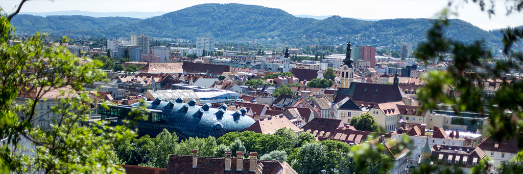 View of the Graz Art museum and the Old Town surrounded by other buildings and green hills