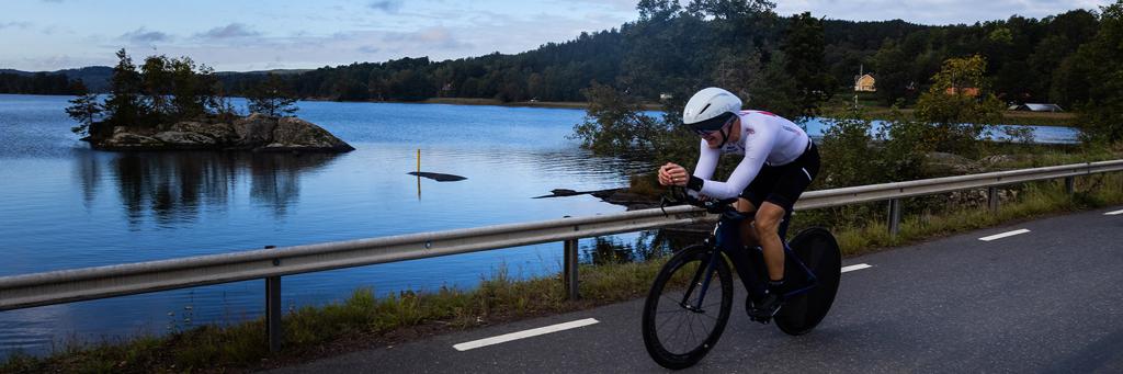 Single athlete biking through a along a Lake with a beautiful view  IRONMAN 70.3 Jönköping