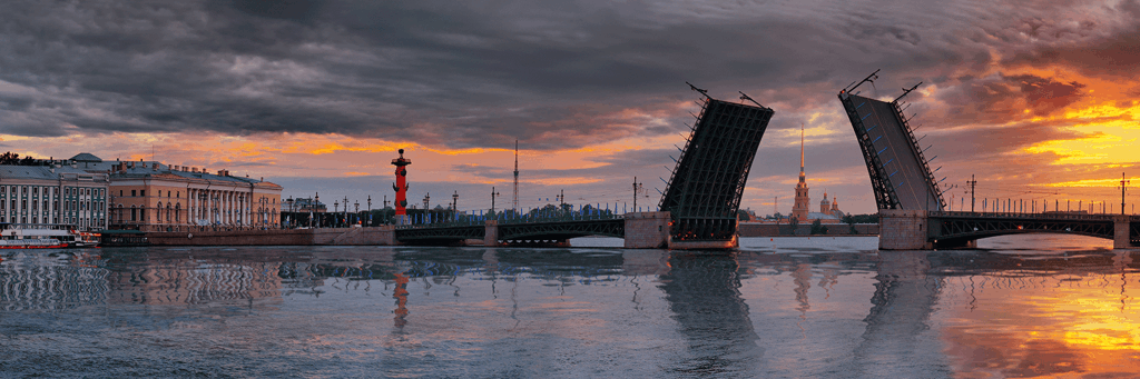 The palace bridge at the Neva river and the Palace Square seen between the raising bridge at sunset which colors the sky yellow in St. Petersburg