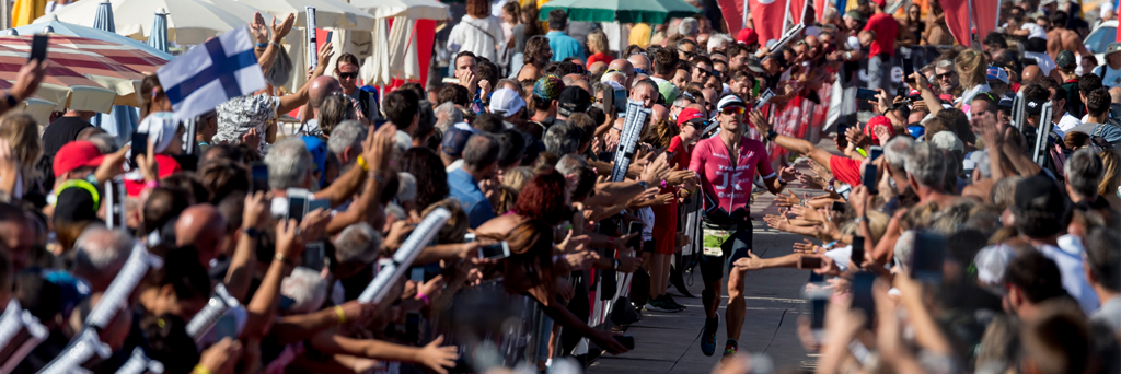 Athlete entering the Finish Line in Cervia with a massive crowd cheering him on at IRONMAN Italy Emilia-Romagna