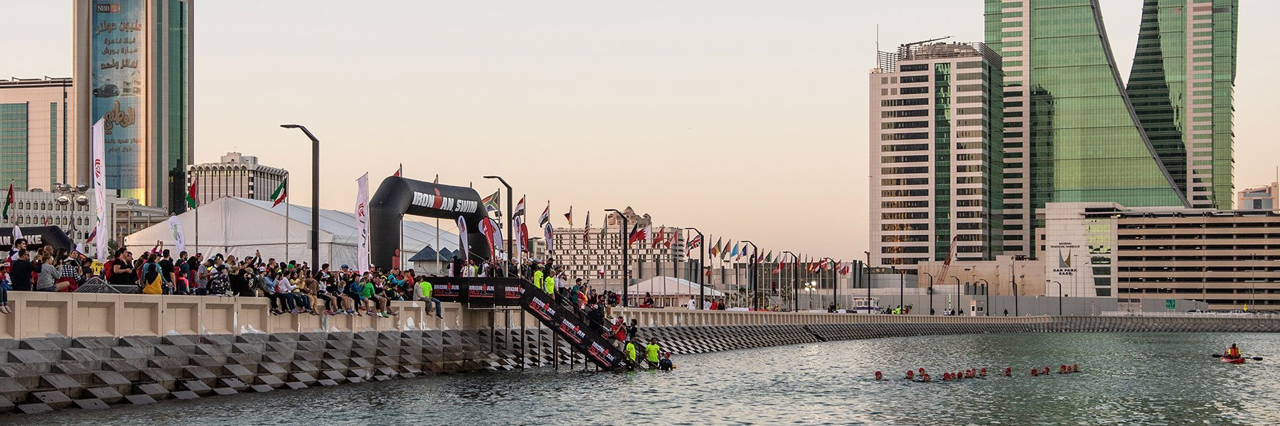 IRONMAN 70.3 Bahrain athletes are in the water in front of "The Avenues" in Manama and wait for the signal of the swim start, while people are watching