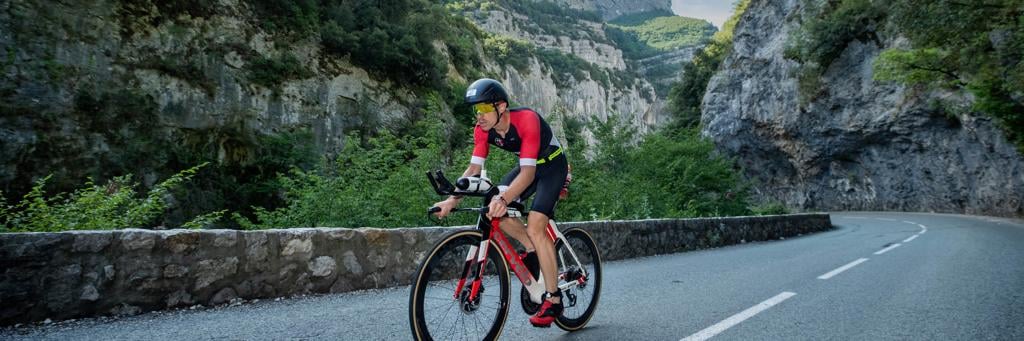 IRONMAN 70.3 Nice athlete biking through a valley of green covered hills