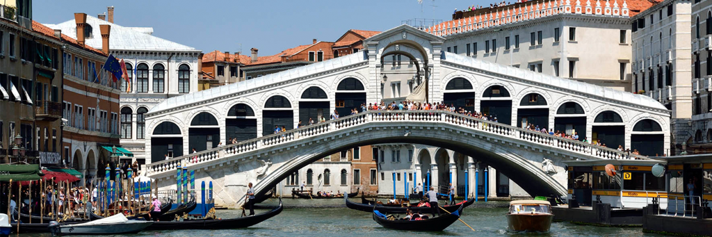 Famous white Rialto bridge in Venice, which is crossed by many tourists and under which a few gondolas pass