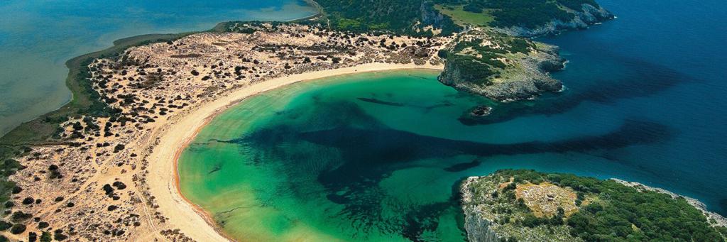 Voidokilia Beach with dark blue and green shining water and semicircular strip of dunes in the Mediterranean area at Costa Navarino Greece