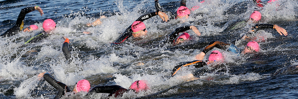 IRONMAN 70.3 Staffordshire athletes with pink swim caps are swimming in Chasewater