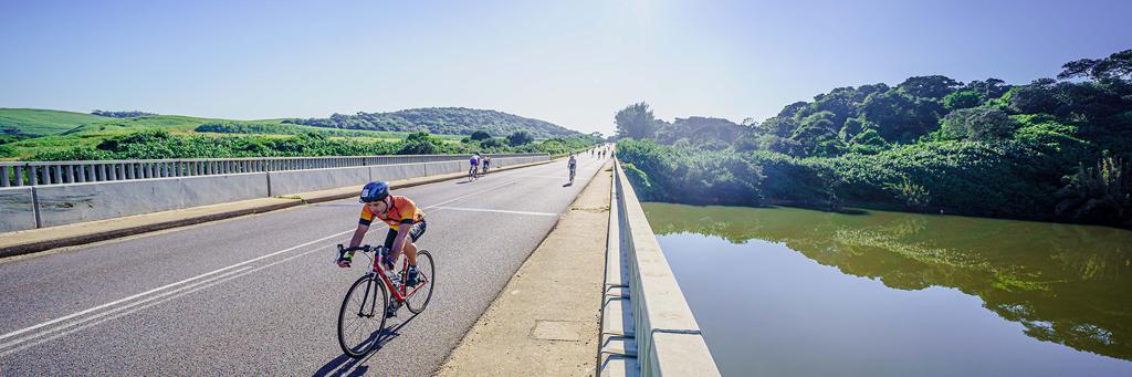 IRONMAN 70.3 Durban athletes are biking on a fast and undulating course across a bridge with green hills on the left and right side