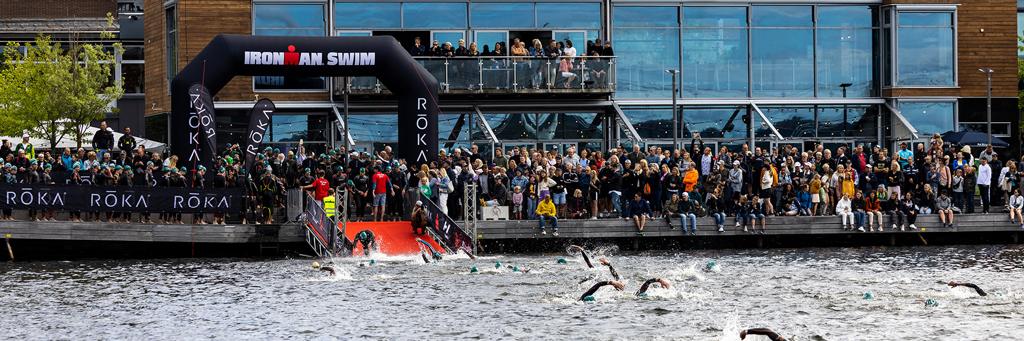 Swim start at IRONMAN 70.3 Jönköping with athletes entering the sea and many supporters watching