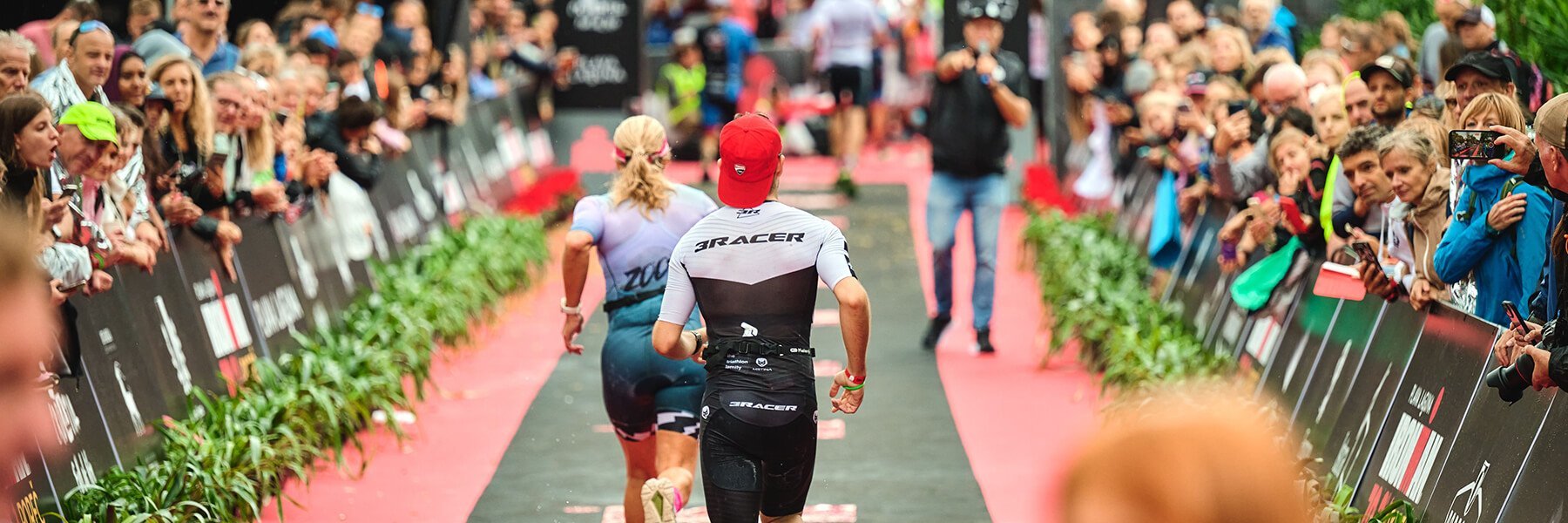 Two athletes running to the Finish Line cheered on by supporters at Plava Laguna IRONMAN 70.3 Porec Croatia