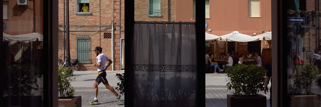 Athlete running through the heart of Cervia seen through a store at IRONMAN Italy Emilia-Romagna