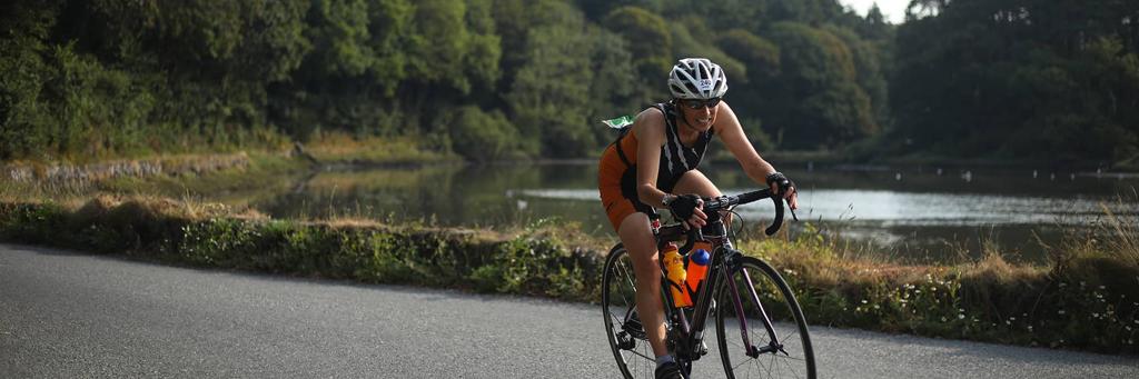 IRONMAN Ireland Cork athletes biking on a lane surrounded by trees and fields on a rainy day