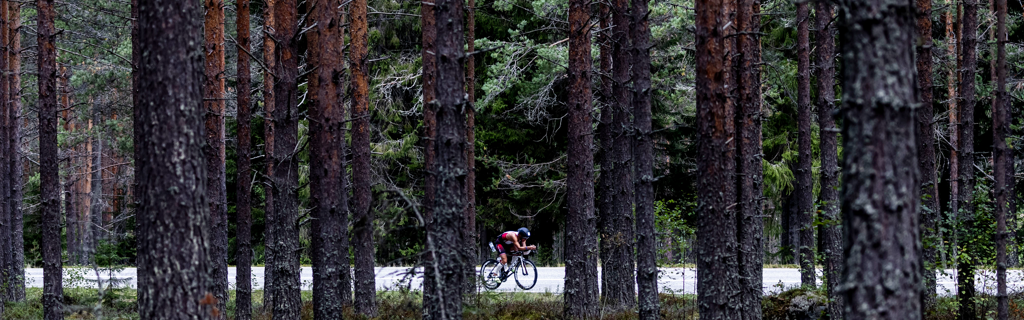 Athlete biking on the street surrounded by woods in Kuopio-Tahko Finland