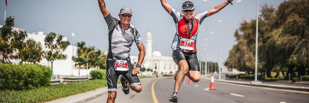 Two athletes jumping for an image on the run course of IRONMAN 70.3 Oman