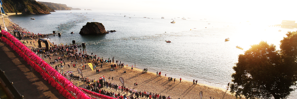 IRONMAN Wales swim course at famous Tenby North Beach with viewing the Goscar Rock, the sea and participants and supporters at sunrise