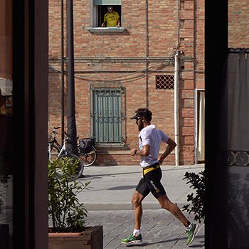 An athlete running through streets in the old town of Cervia seen from a restaurant