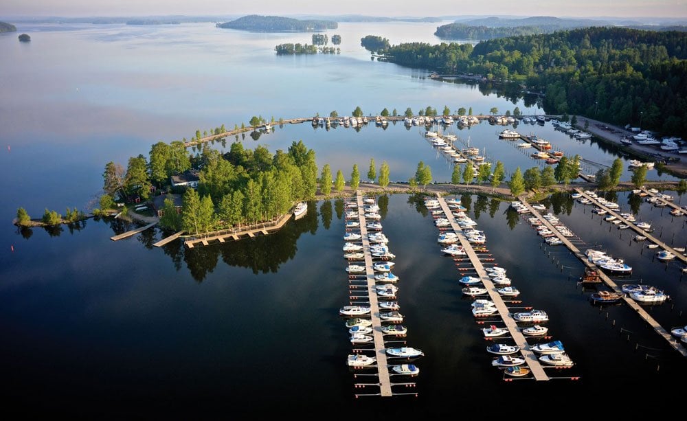 Bird's eye view of boats on docks and some small islands covered with trees in a beautiful lake in Lahti, Finland