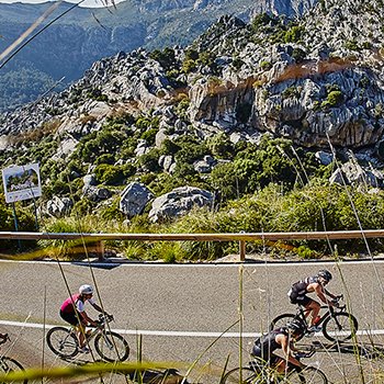IRONMAN 70.3 Alcúdia-Mallorca athletes biking up a hill around Pollenca