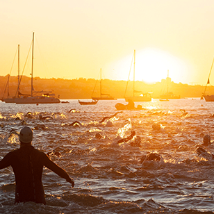 Athletes swimming at Pescadores Beach in Cascais at sunrise